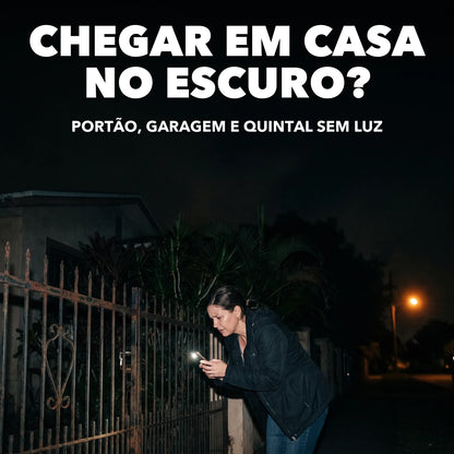 Mulher procurando a fechadura do portão no escuro com a lanterna do celular